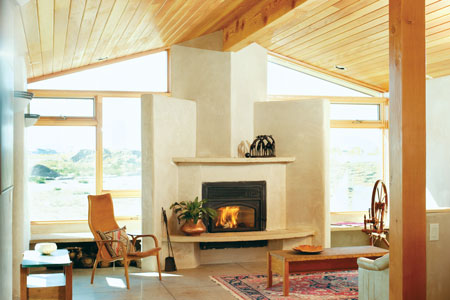 ABOVE: The living room features Douglas fir ceilings, an energyefficient fireplace built into winged walls, and polished cement floors, into which a radiant in-floor heating system has been built. The concrete floors were ground smooth, then retroplated in a glass-like sealing process so they never need to be waxed. Alden Amos made the spinning wheel.